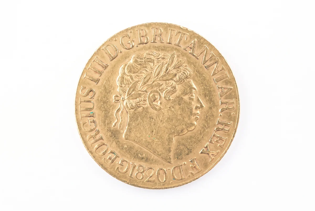 A close-up of a gold coin displaying a man's portrait, highlighting its craftsmanship and shiny surface.